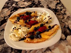 a plate of pancakes with fruit and whipped cream at Domy z Bala - Bungalow 50 metrów od Plaży spa domki ogrzewane in Dziwnówek