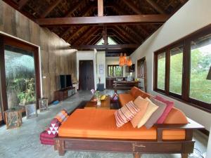 ein Wohnzimmer mit einem orangenen Sofa in einem Zimmer mit Fenstern in der Unterkunft Hill Top Retreat by Sea Dance Resort in Koh Samui 