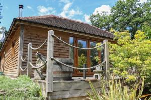 uma cabana de madeira com um alpendre com um baloiço em Garden Cottage em Farnham