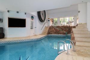 a swimming pool in a house with a tv and stairs at Garden Cottage in Farnham