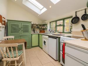 cocina con armarios verdes y lavavajillas en Damson Cottage, en Bridgwater