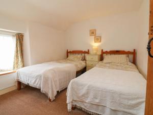 a bedroom with two beds and a window at Damson Cottage in Bridgwater