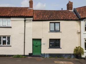 a white house with a green door on a street at Damson Cottage in Bridgwater