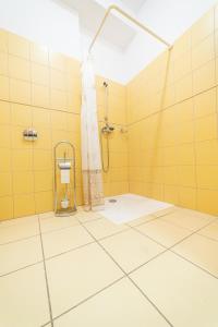 a bathroom with yellow tiled walls and a shower at Ośrodek Wrzosowa Góra - pokoje in Ruciane-Nida