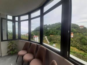 een kamer met een rij ramen met stoelen en uitzicht bij Müstakil villa in Trabzon