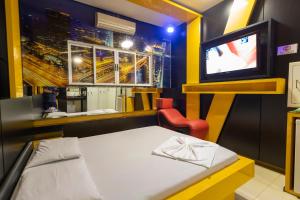 a small room with a bed and a tv at Troia Motel in Foz do Iguaçu