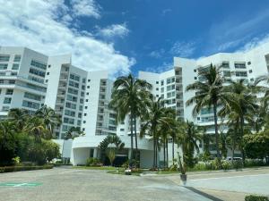 um grande edifício branco com palmeiras em frente em Departamento Playa Punta Diamante em Acapulco