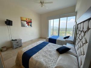 um quarto com 2 camas e uma grande janela em Departamento Playa Punta Diamante em Acapulco