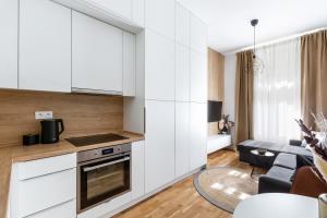 a kitchen with white cabinets and a living room at TurnKey I Cozy Studio by Letna Park in Prague