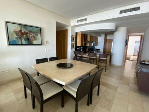 a dining room and living room with a table and chairs at Mayan Playa Departamento Tikal in Acapulco