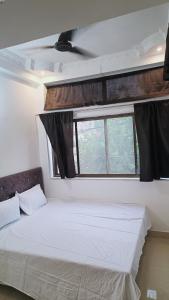 a white bed in a room with a window at Hotel 100 Meter in Jabalpur