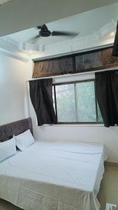 a bedroom with a white bed with a window at Hotel 100 Meter in Jabalpur