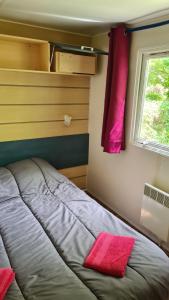 a bedroom with a bed and a window with pink pillows at Mobil-Home 1à 4 Personnes in Attigny