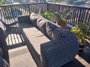 a wicker bench sitting on a balcony with plants at Busis guesthouse in Durban