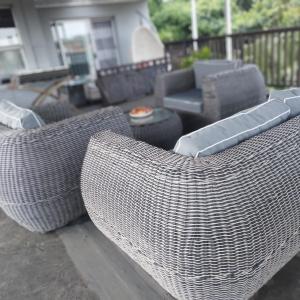 two wicker chairs on a porch with a couch at Busis guesthouse in Durban