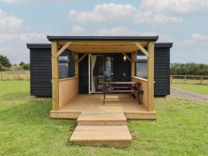 a black tiny house with a wooden porch and a bench at River Lodge in Aldeburgh