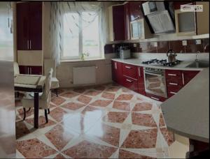 a kitchen with red cabinets and a table and a stove at Bulvar in Ivano-Frankivsk