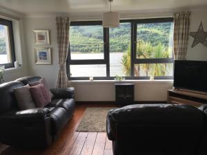 a living room with a couch and a large window at Heron’s View in Arrochar