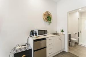 a kitchen with a sink and a microwave on a counter at Cosy Studio in Central Avondale - Netflix Wi-Fi in Auckland