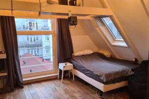 a small bedroom with a bed and two windows at Groot mooi 2 etage loft met dakterras in De Pijp. in Amsterdam