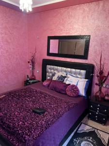 una camera rosa con un grande letto con lenzuola viola di Mohammédia Marbella beach appartement familliale a Minaret de Mansuria