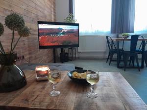 a table with two glasses of wine and a television at Apartmán Maya in Pardubice
