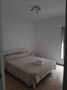 - une chambre blanche avec un lit et 2 serviettes dans l'établissement Apartamento Juan, à Vejer de la Frontera