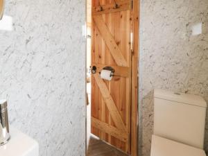 Baño con puerta de madera junto a un aseo en Greenacres Carriage, en Maybole