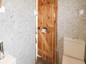 a bathroom with a wooden door next to a toilet at Greenacres Carriage in Maybole
