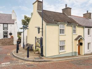 a yellow building with a bench in a street at Bwthyn Lili Lily Cottage in Cemaes Bay
