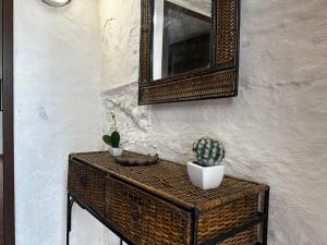 a wicker table with a cactus and a mirror on a wall at LA CUEVA de TONI EL SECO in Paterna