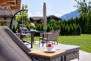 a patio with a table and chairs and a table with a drink at Tennerhof Luxury Chalets in Kitzbühel