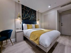 a bedroom with a large bed and a chair at NOX Kensington Gardens in London +36 photos