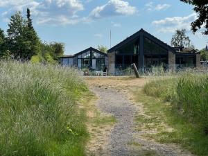 un bâtiment avec un chemin de terre devant lui dans l'établissement Luksus hus i 1st række, all-incl top komfort med SPA og skov, à Strøby