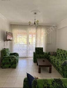 ein Wohnzimmer mit grünen Sofas und einem Tisch in der Unterkunft KARAAGAC GÖMEC in Burhaniye