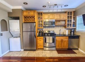 a kitchen with wooden cabinets and stainless steel appliances at Romance in the City 1 Bdrm Studio in Downtown St Pete in St Petersburg