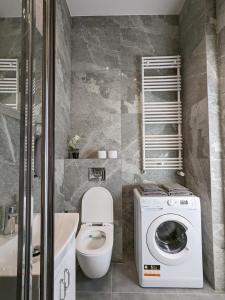 a bathroom with a toilet and a washing machine at OstWestApart A31 in Warsaw
