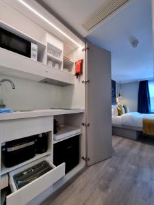 a kitchen with white cabinets and a bed in a room at NOX Kensington Gardens in London