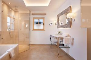 a bathroom with a tub and a sink and a shower at Tennerhof Luxury Chalets in Kitzbühel