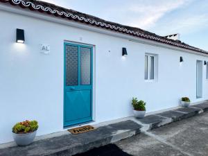 una casa blanca con una puerta azul y algunas plantas en Casa da Fonte - Alojamento Local com Jacuzzi, en Nordeste