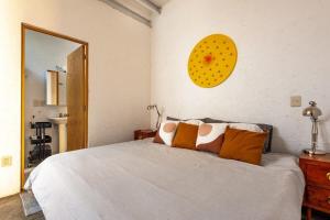 a bedroom with a white bed with a yellow clock on the wall at Amazing loft w/ terrace in Mexico City Downtown in Mexico City