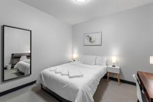 a white bedroom with a large white bed and a mirror at Journal Commons 325 Luxurious Cozy 1BR near Historic Third Ward in Milwaukee