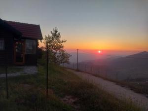 een zonsondergang op een heuvel met een huis en een hek bij בקתות קסם חרמון in Nimrod