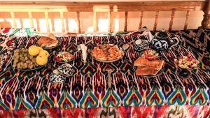 einen Tisch mit Teller mit Lebensmitteln auf einem Bett in der Unterkunft Shirin House Guest House in Buxoro