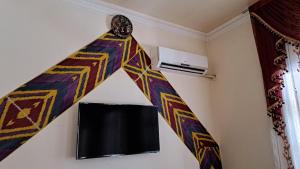 Zimmer mit einem Vorhang und einem TV an der Wand in der Unterkunft Shirin House Guest House in Buxoro