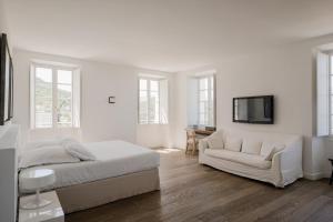 Habitación blanca con cama y sofá en Aethos Corsica, en Oletta
