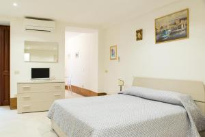 ein weißes Schlafzimmer mit einem Bett und einem TV in der Unterkunft Cannaregio -Cozy and central flat with private patio in Venedig