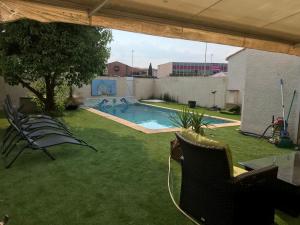 einen Hinterhof mit Pool und Stühlen im Gras in der Unterkunft Villa 10 pers +Piscine + parking in Lattes