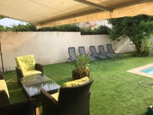 eine Terrasse mit Stühlen, einem Tisch und Gras in der Unterkunft Villa 10 pers +Piscine + parking in Lattes