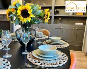 a dining room table with a vase of sunflowers and plates at Real Lush Properties - Spacious Four-Bedroom House, Ideal for Families & Contractors , Burton in Burton upon Trent